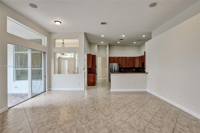 kitchen featuring stainless steel fridge with ice dispenser, light tile patterned floors, and kitchen peninsula