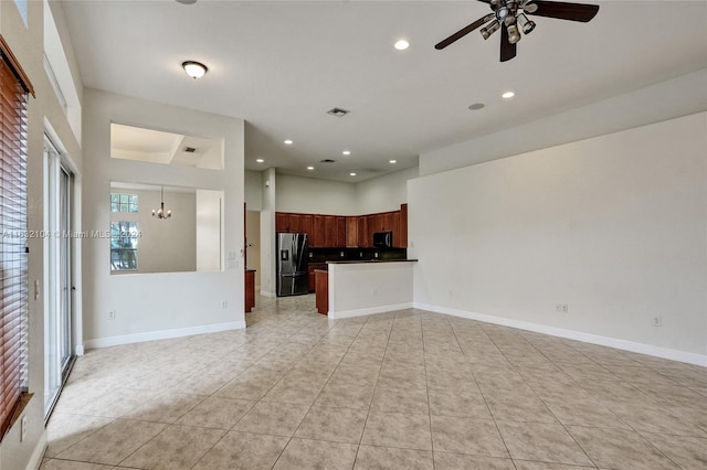 unfurnished living room with ceiling fan with notable chandelier and light tile patterned flooring