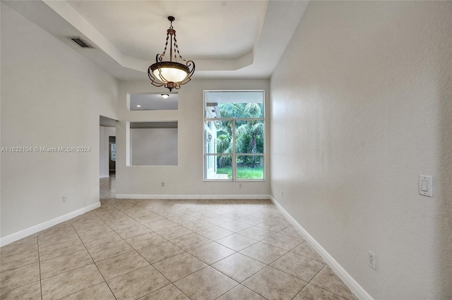 spare room featuring light tile patterned floors and a raised ceiling