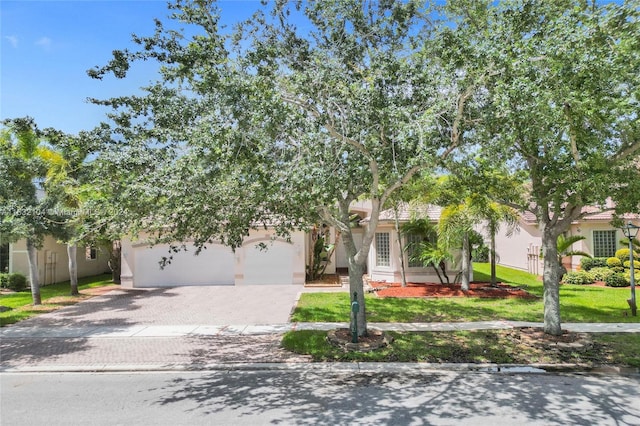 view of property hidden behind natural elements featuring a garage and a front lawn