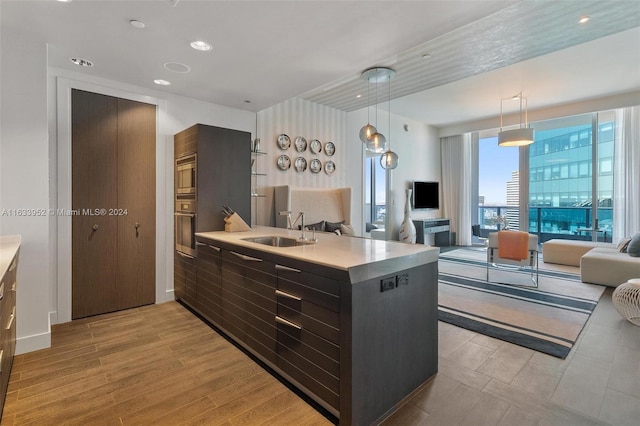 kitchen featuring pendant lighting, stainless steel microwave, sink, kitchen peninsula, and light hardwood / wood-style flooring