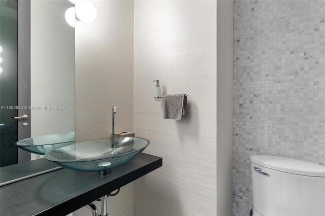 bathroom featuring tile walls, toilet, and sink