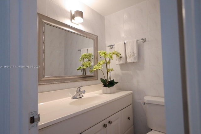 bathroom featuring vanity, toilet, and tile walls