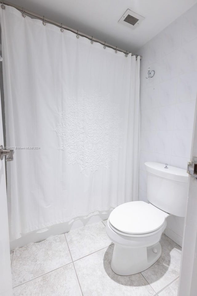 bathroom with tile walls, tile patterned floors, and toilet