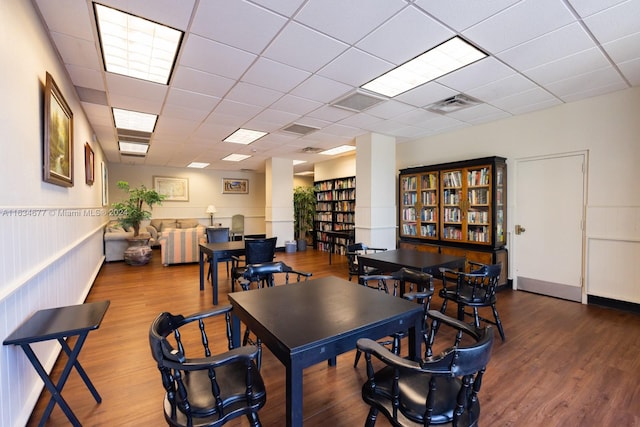 dining space with a drop ceiling and hardwood / wood-style flooring