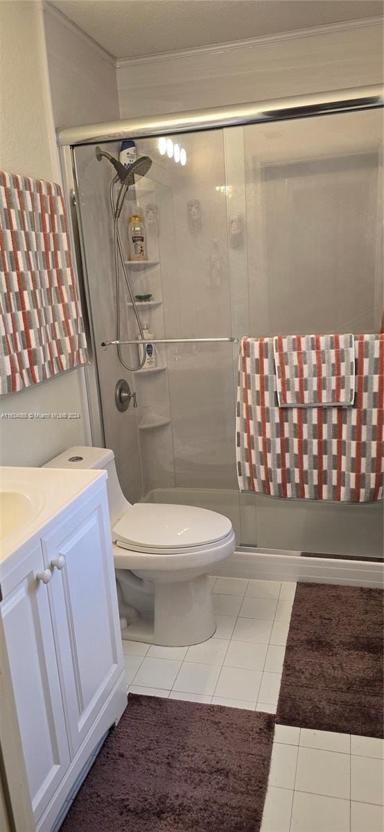 bathroom with tile patterned floors, vanity, toilet, and a shower with shower door