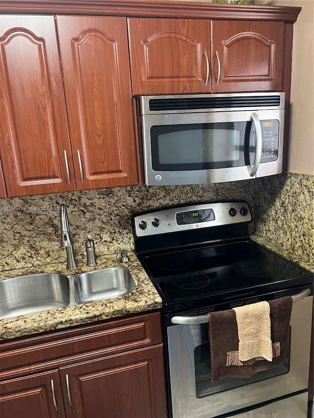 kitchen with stone counters, appliances with stainless steel finishes, backsplash, and sink