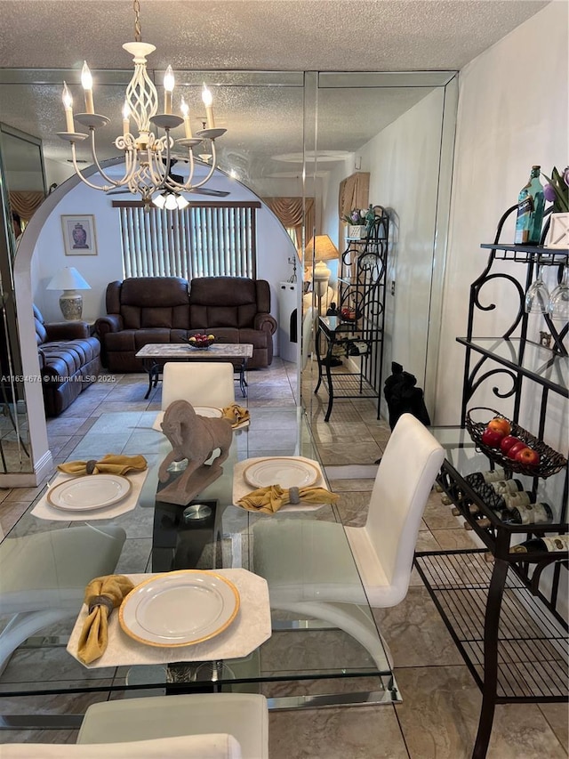 dining space with ceiling fan with notable chandelier and a textured ceiling