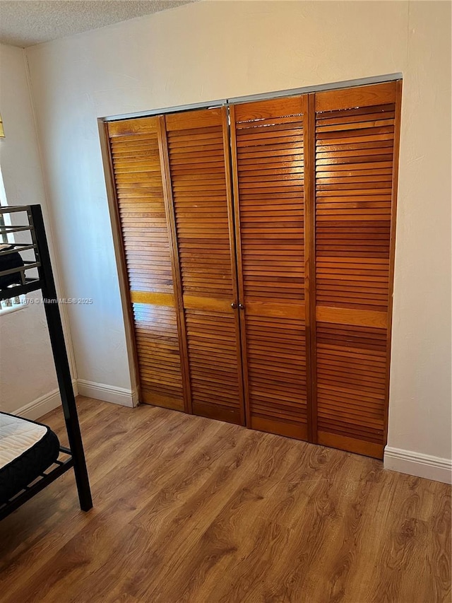 unfurnished bedroom featuring a closet, wood-type flooring, and a textured ceiling