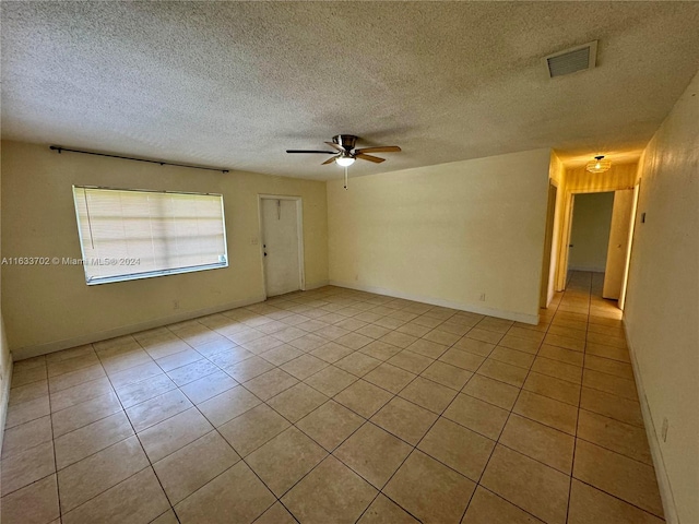 spare room with light tile patterned flooring, a textured ceiling, and ceiling fan