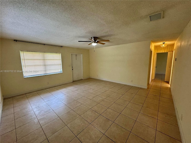 tiled empty room with ceiling fan and a textured ceiling