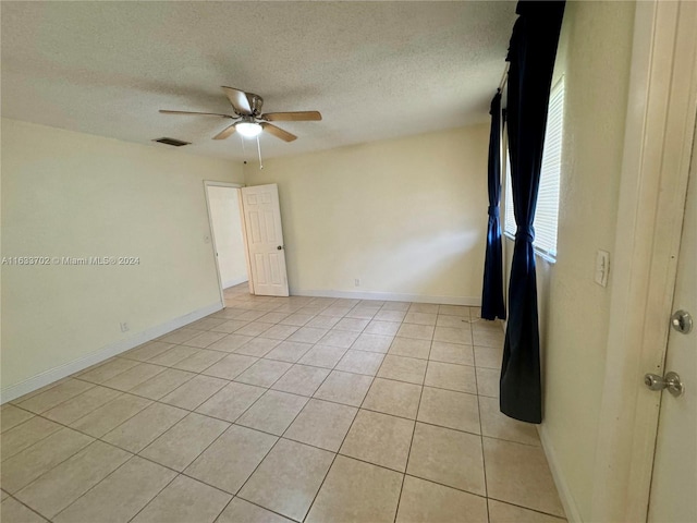 spare room with light tile patterned flooring, a textured ceiling, and ceiling fan