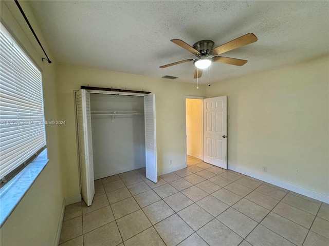 unfurnished bedroom with a closet, light tile patterned floors, a textured ceiling, and ceiling fan