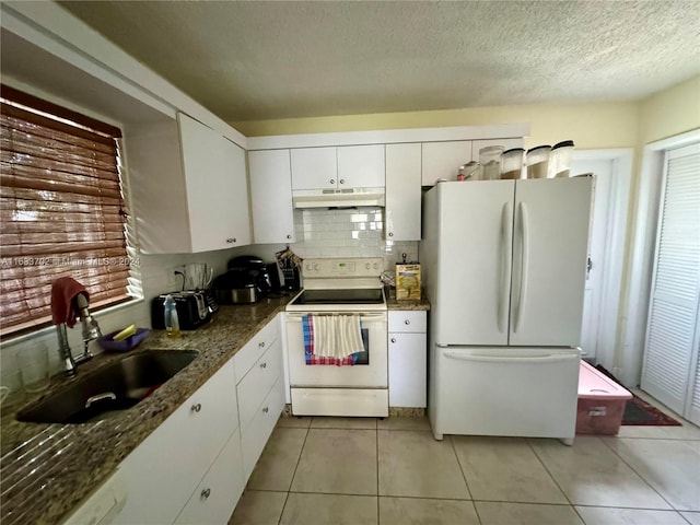 kitchen with white appliances, light tile patterned floors, white cabinets, backsplash, and sink