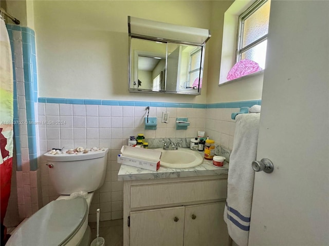 bathroom featuring vanity, toilet, backsplash, and tile walls