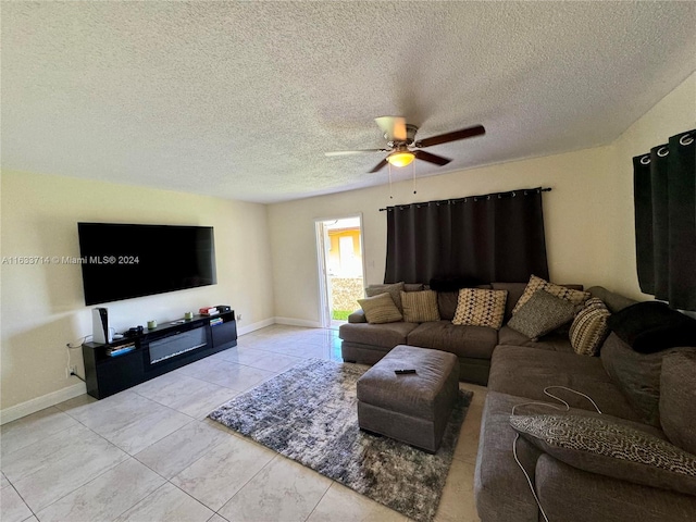 living room featuring ceiling fan, light tile patterned floors, and a textured ceiling