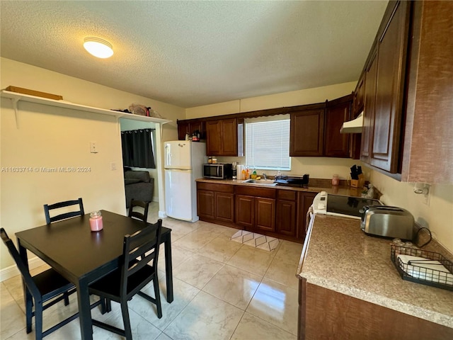 kitchen featuring stove, white refrigerator, a textured ceiling, light tile patterned flooring, and wall chimney exhaust hood