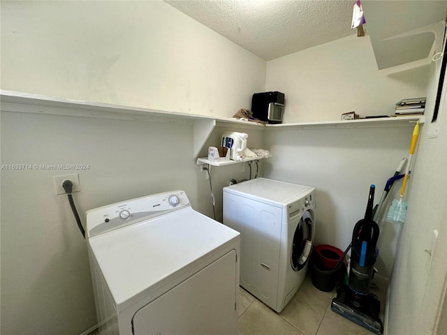 washroom featuring washing machine and dryer, a textured ceiling, and light tile patterned floors