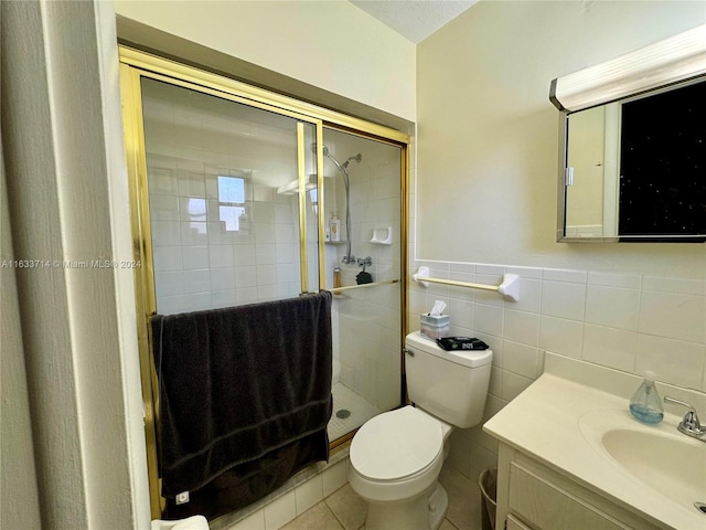 bathroom with vanity, tile walls, a tile shower, toilet, and tile patterned flooring