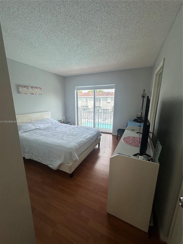 bedroom with a textured ceiling, dark hardwood / wood-style flooring, and access to exterior