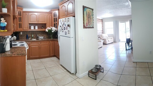 kitchen with decorative backsplash, white refrigerator, light tile patterned flooring, and a textured ceiling