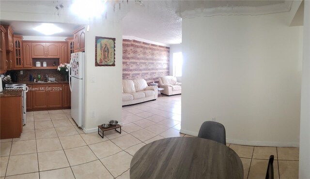 kitchen featuring decorative backsplash, white appliances, a textured ceiling, sink, and light tile patterned floors