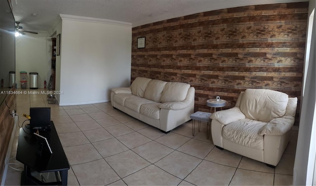 living room featuring ceiling fan, wood walls, a textured ceiling, light tile patterned floors, and ornamental molding