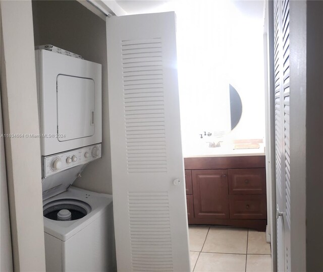 laundry area with sink, stacked washer / dryer, and light tile patterned flooring