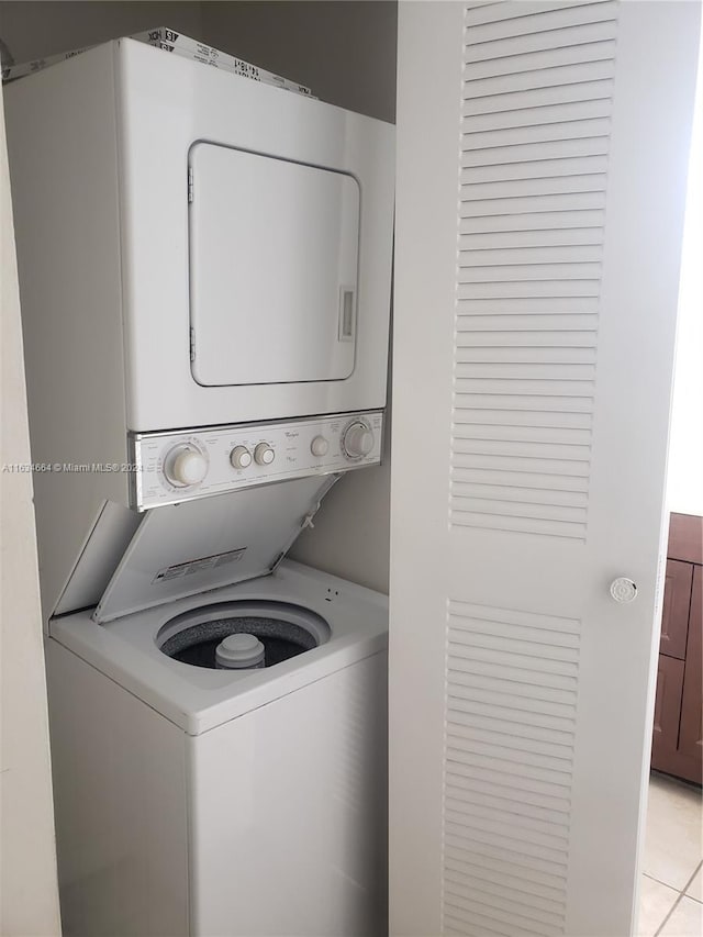 laundry area featuring stacked washer and dryer and light tile patterned flooring