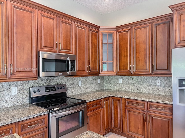 kitchen with backsplash, light stone countertops, and appliances with stainless steel finishes