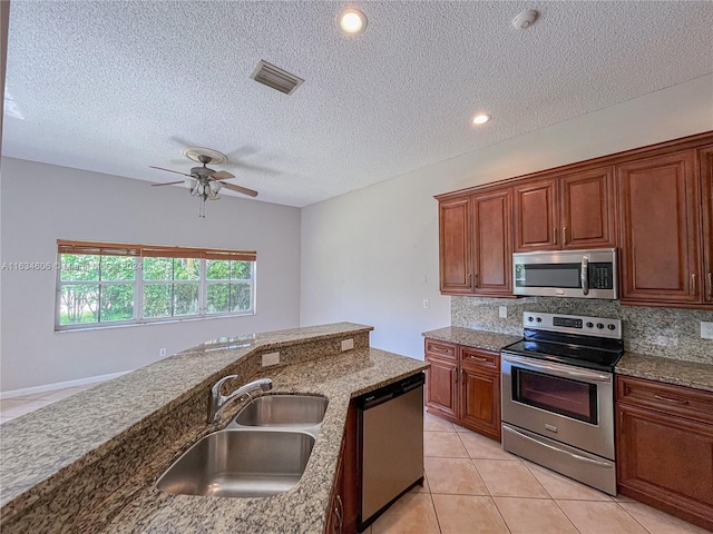 kitchen with light tile patterned flooring, ceiling fan, sink, appliances with stainless steel finishes, and backsplash