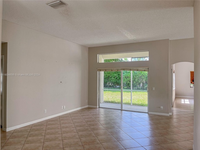 tiled empty room featuring a towering ceiling and a textured ceiling