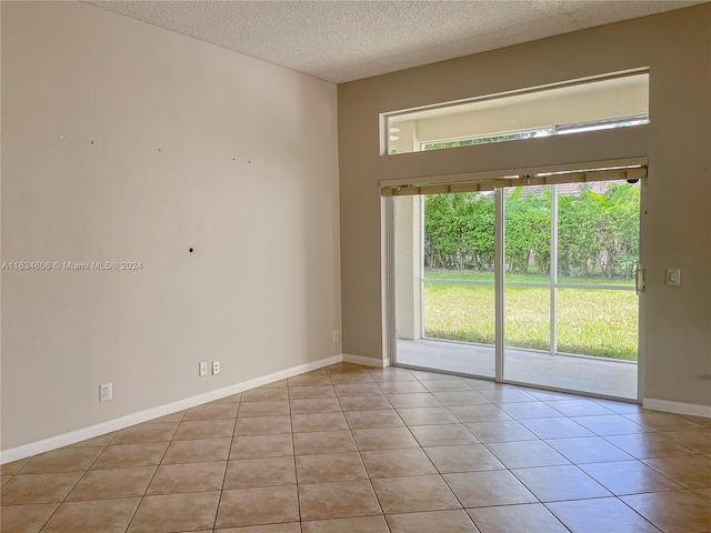 unfurnished room with a textured ceiling and light tile patterned floors