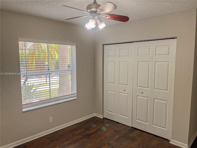 unfurnished bedroom with dark wood-type flooring, a closet, and ceiling fan