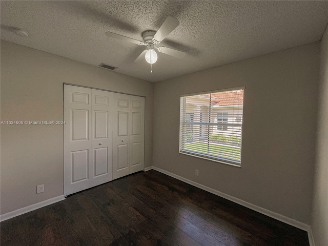 unfurnished bedroom with a closet, a textured ceiling, ceiling fan, and dark hardwood / wood-style floors