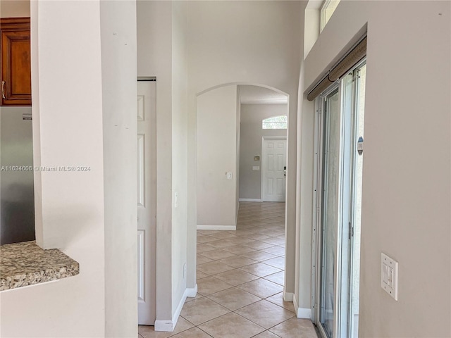 hallway featuring a towering ceiling and light tile patterned floors