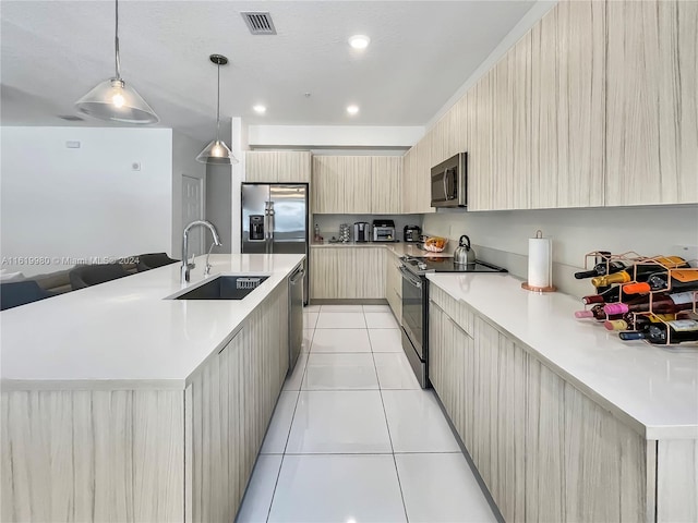 kitchen with appliances with stainless steel finishes, light brown cabinetry, sink, pendant lighting, and a large island with sink