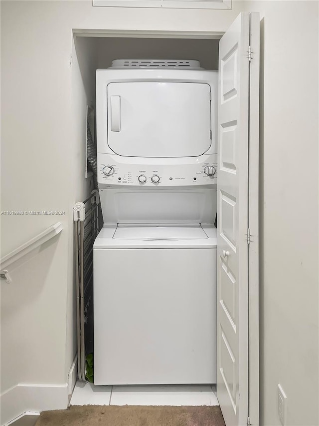 laundry room with tile patterned flooring and stacked washer and dryer