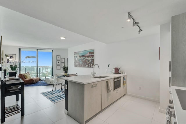 kitchen with sink, rail lighting, kitchen peninsula, oven, and light tile patterned floors