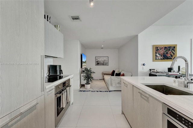 kitchen with light brown cabinets, light tile patterned floors, sink, and stainless steel appliances