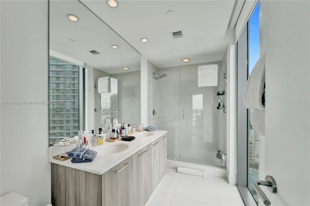 bathroom with tile patterned flooring, vanity, and walk in shower