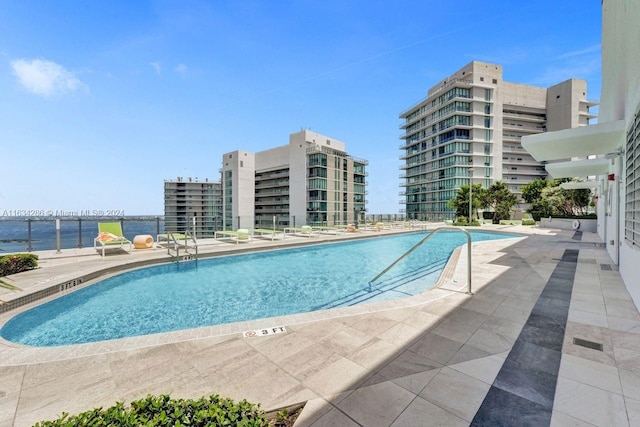 view of swimming pool featuring a water view and a patio