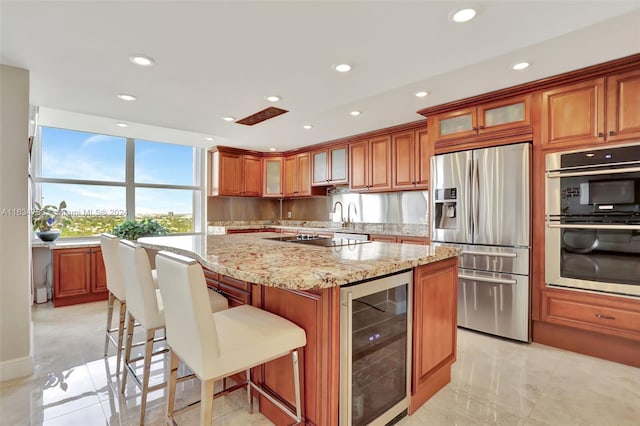 kitchen featuring wine cooler, a kitchen breakfast bar, a center island, light stone countertops, and appliances with stainless steel finishes