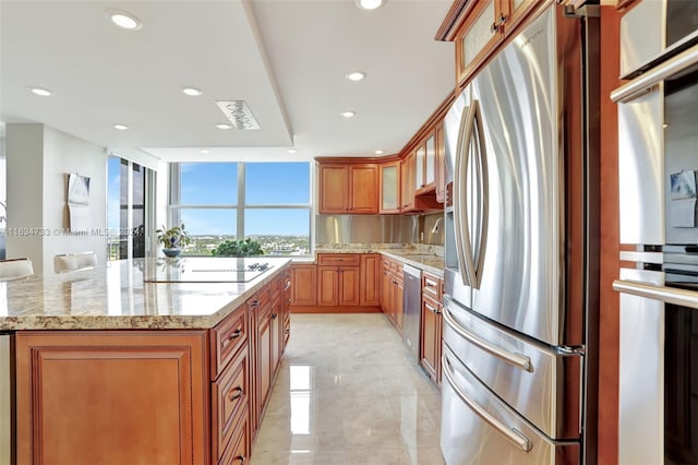 kitchen featuring appliances with stainless steel finishes, light stone counters, and a kitchen island