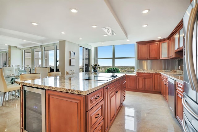 kitchen with a kitchen island, light stone counters, stainless steel appliances, and wine cooler