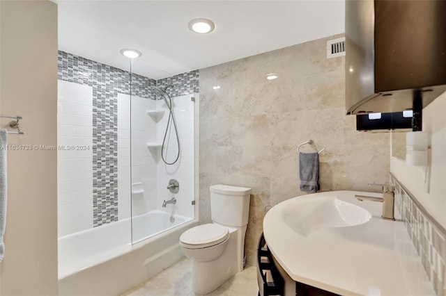 full bathroom with vanity, tile walls, toilet, tiled shower / bath, and tile patterned floors