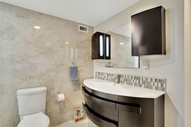 bathroom with vanity, toilet, tile walls, and decorative backsplash