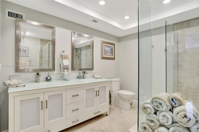 bathroom featuring toilet, a shower with door, decorative backsplash, and vanity