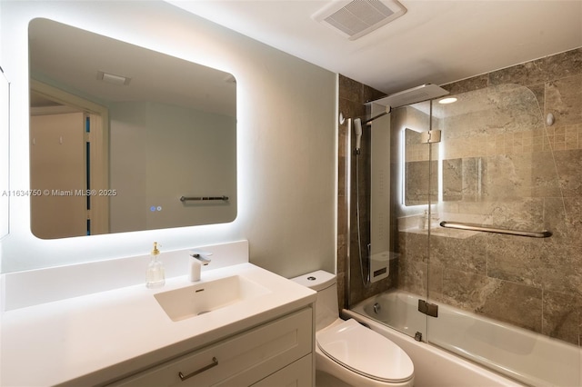 full bathroom with toilet, vanity, and bath / shower combo with glass door