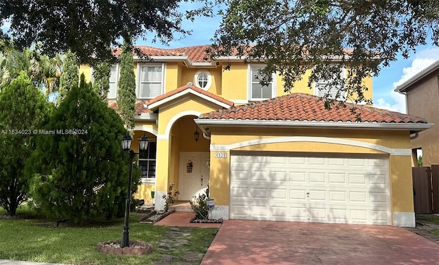 mediterranean / spanish-style house with a garage and a front lawn